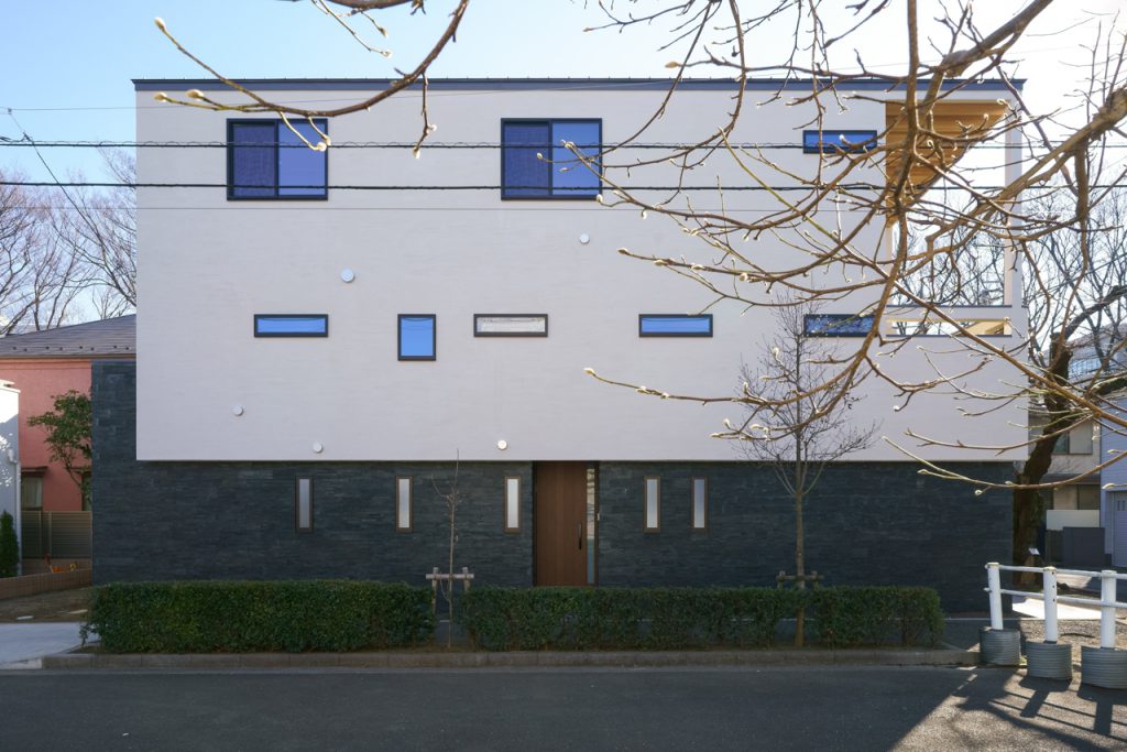 黒い天然石を貼った1階の上に2,3階の白い箱が乗る外観