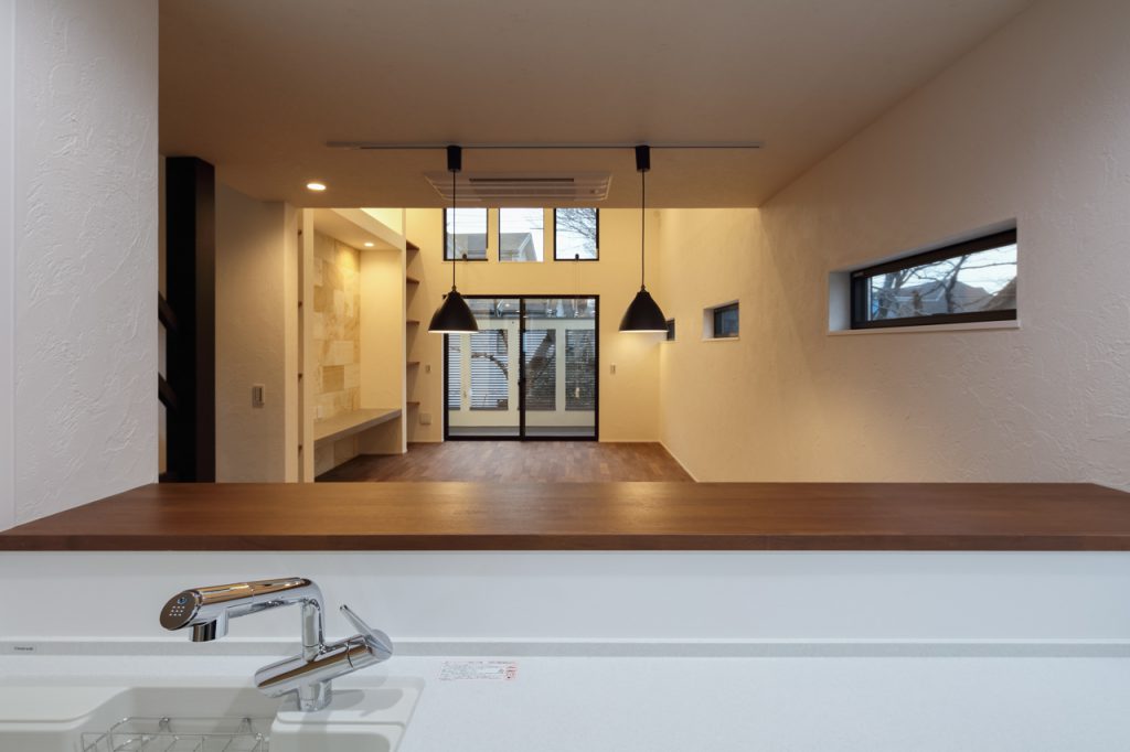 漆喰や天然石が壁に張られ吹き抜けたリビングのあるLDK