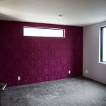 カーペットの床にアクセントのクロスを貼られた寝室