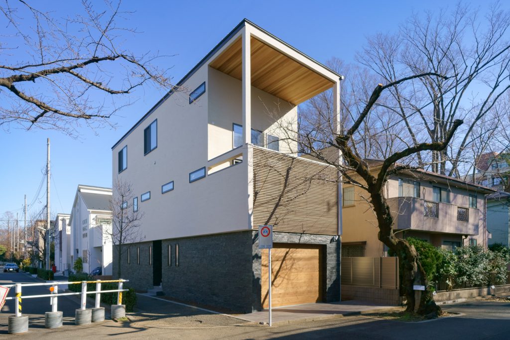 角地の土地に建ち屋根のかかった屋外テラスが道路に面する